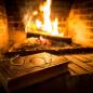 Preview: Buch und Brille im Vordergrund und Kamin mit Feuer im Hintergrund